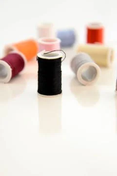 Multi colored thread spools, needle and red button Stock Photos