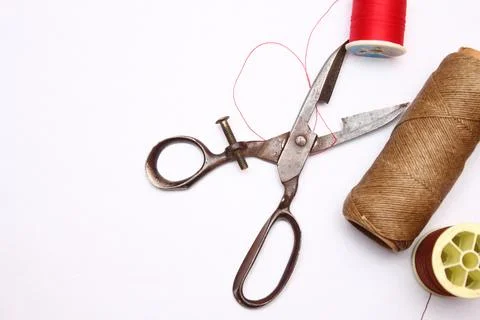 Multi-colored threads and old scissors spread out on a white floor, retro s.. Stock Photos