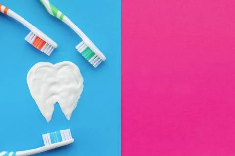 Multi-colored toothbrushes on a blue and pink background with a tooth pattern Stock Photos
