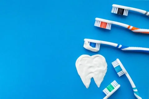 Multi-colored toothbrushes on a blue background with a tooth pattern drawn wi Stock Photos