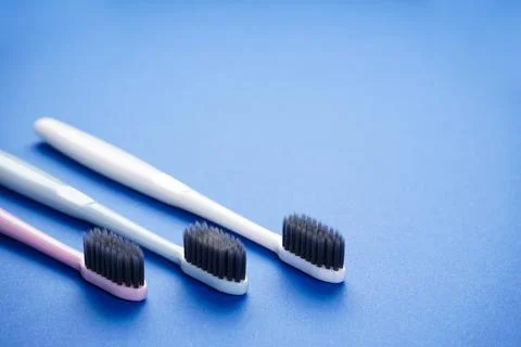 Multi-colored toothbrushes on a blue background with space for text, flat lay Stock Photos