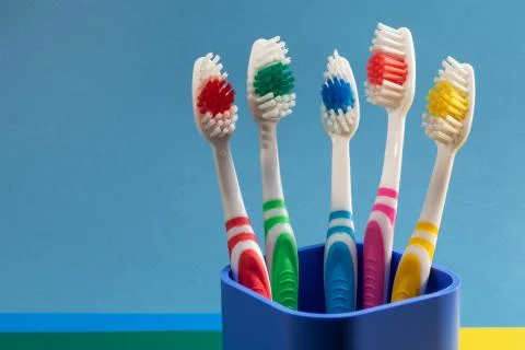 Multi-colored toothbrushes in a plastic сup Stock Photos
