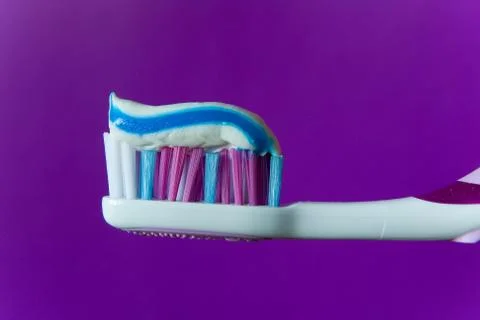 A multi-colored toothpaste is applied to a multi-colored toothbrush. Stock Photos