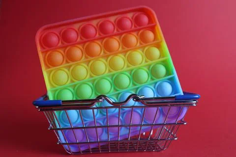 The multi-colored toy is a popit simple dimple anti-stress in a basket of str Stock Photos