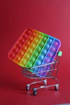 The multi-colored toy is a popit simple dimple anti-stress in a basket of str Stock Photos
