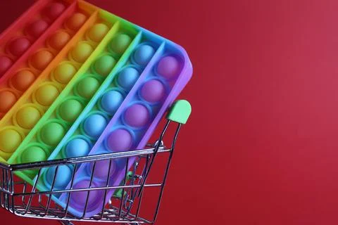 The multi-colored toy is a popit simple dimple anti-stress in a basket of str Stock Photos