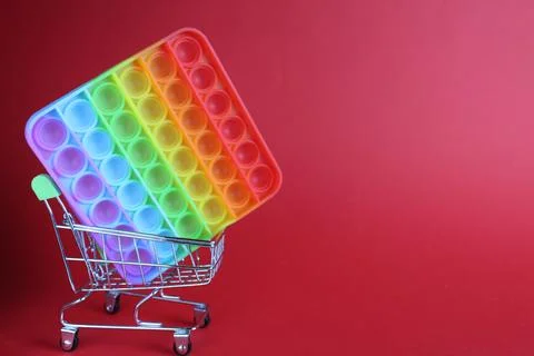 The multi-colored toy is a popit simple dimple anti-stress in a basket of str Stock Photos