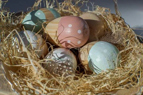 Multi-colored wooden Easter eggs lie in a paper nest Stock Photos