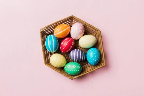 Multi colors Easter eggs in the woven basket on colored background . Pastel c Stock Photos