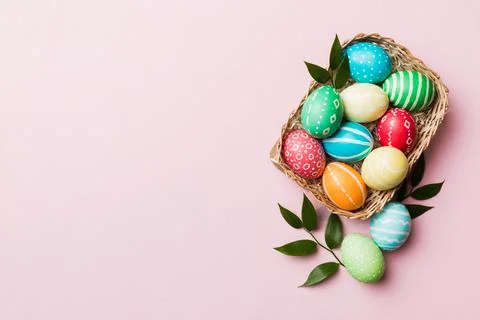Multi colors Easter eggs in the woven basket on colored background . Pastel c Stock Photos
