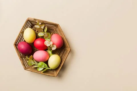 Multi colors Easter eggs in the woven basket on colored background . Pastel c 스톡 사진