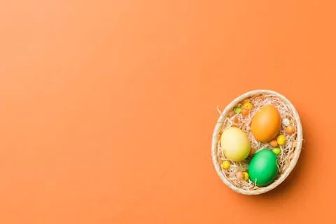Multi colors Easter eggs in the woven basket on colored background . Pastel c Stockfoto's