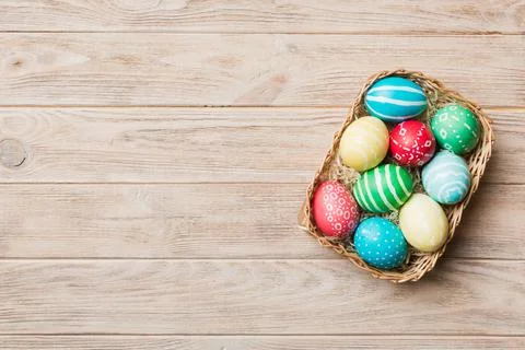 Multi colors Easter eggs in the woven basket on colored background . Pastel c Stock Photos
