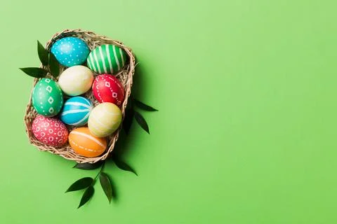 Multi colors Easter eggs in the woven basket on colored background . Pastel c Stock Photos