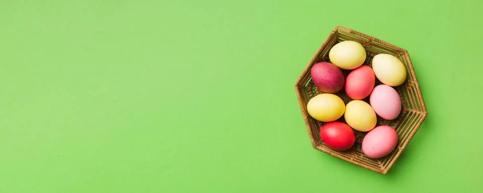 Multi colors Easter eggs in the woven basket on colored background . Pastel.. 写真素材