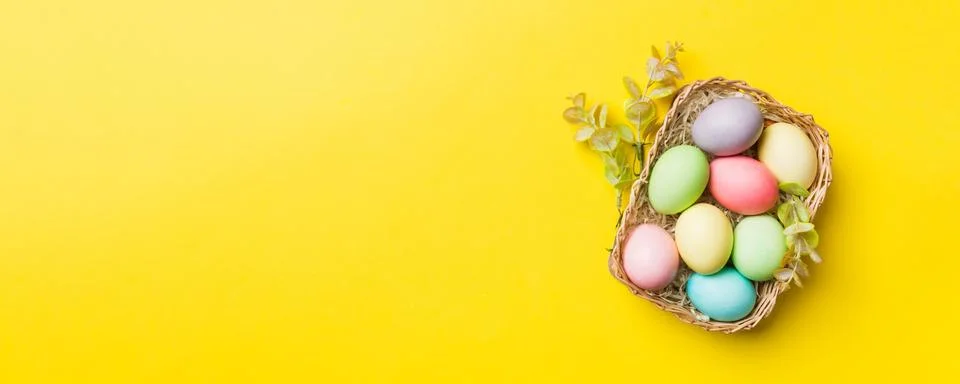 Multi colors Easter eggs in the woven basket on colored background . Pastel c Stock Photos