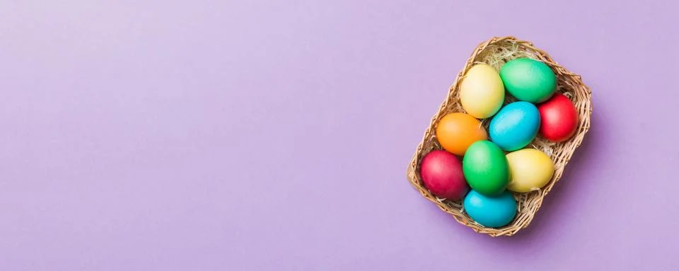 Multi colors Easter eggs in the woven basket on colored background . Pastel.. Stock Photos