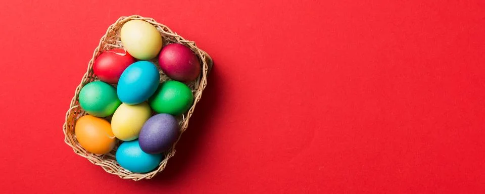 Multi colors Easter eggs in the woven basket on colored background . Pastel c Stock Photos