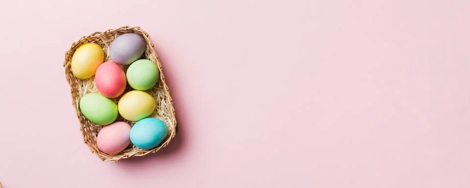 Multi colors Easter eggs in the woven basket on colored background . Pastel.. Foto stock