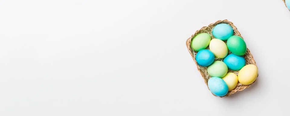 Multi colors Easter eggs in the woven basket on colored background . Pastel c Stock Photos