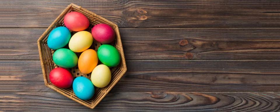 Multi colors Easter eggs in the woven basket on colored background . Pastel c Stock Photos