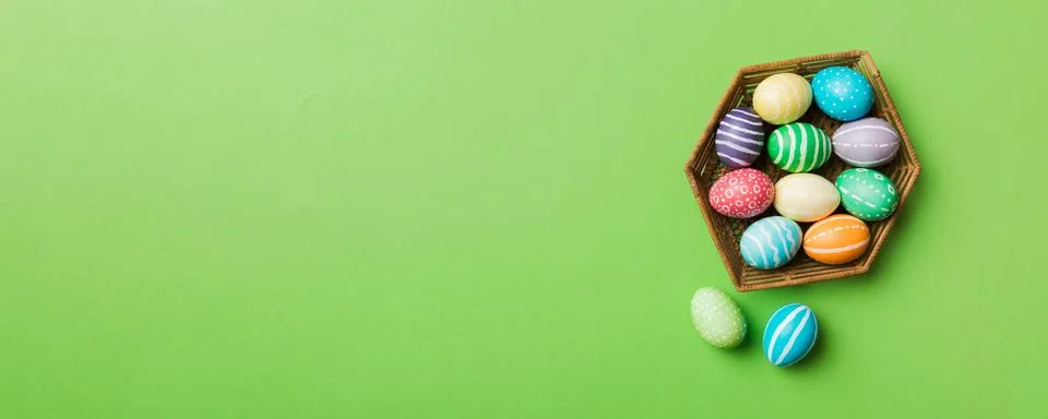 Multi colors Easter eggs in the woven basket on colored background . Pastel.. Stock Photos