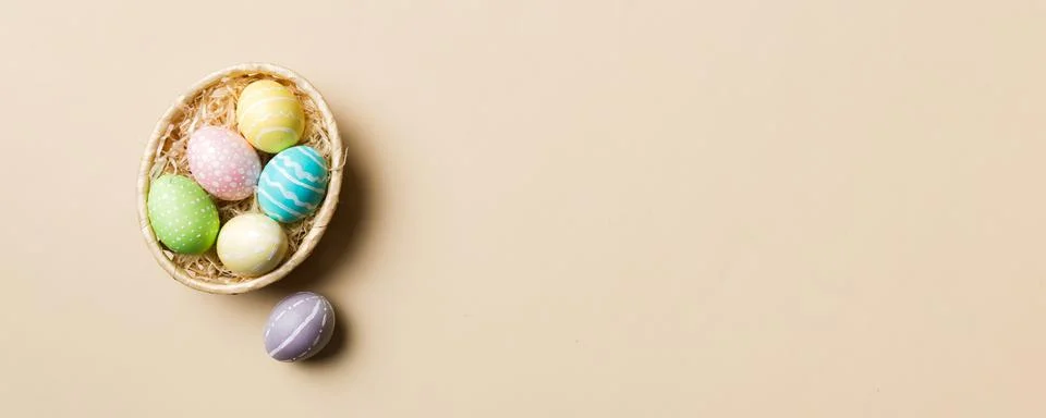 Multi colors Easter eggs in the woven basket on colored background . Pastel.. Stock Photos