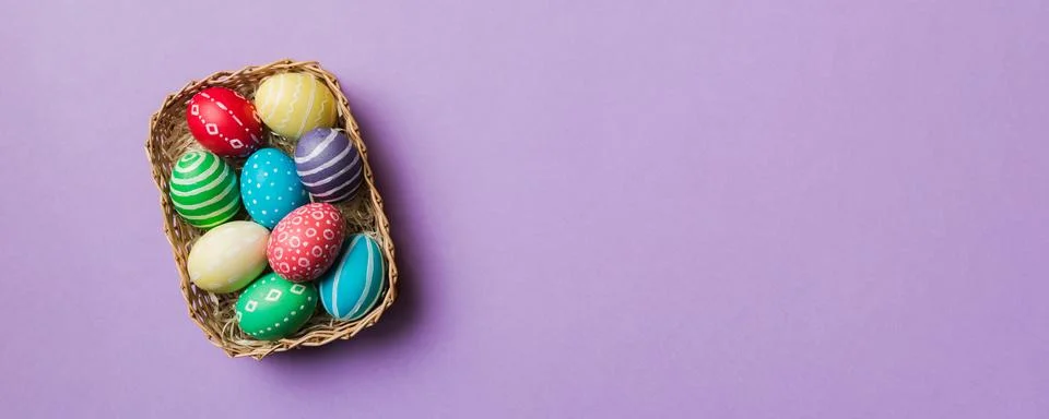 Multi colors Easter eggs in the woven basket on colored background . Pastel.. Stock Photos