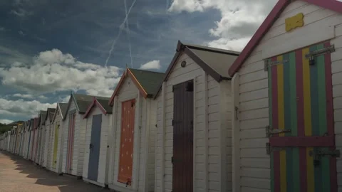 Multi coloured beach huts by the sea clouds passing by Stock Footage 338033860
