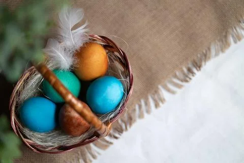 Multi coloured Easter eggs in wicker basket on rustic background 스톡 사진