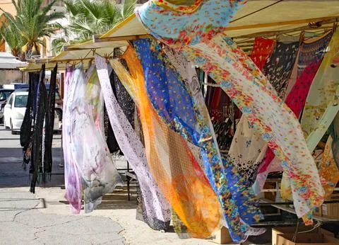 Multi coloured patterned silk scarves blowing in the breeze on a market stall 스톡 사진