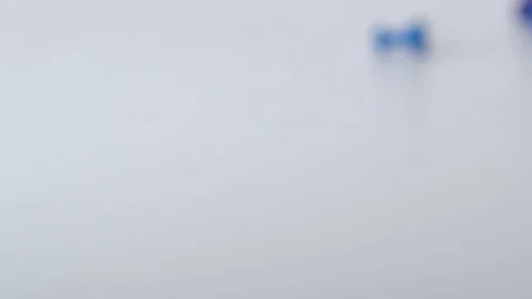 Multi-coloured push pins dropped onto white surface in slow motion Stock Footage 117350162
