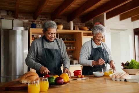 Multi-cultural elderly couple preparing meal in modern kitchen. Colorful Stock Photos