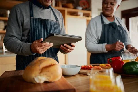 Multi-cultural elderly male using tablet to research recipe in kitchen. Happy Stock Photos
