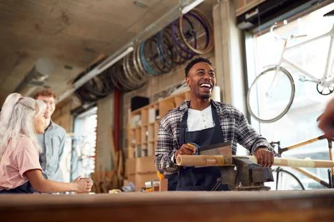 Multi-Cultural Team In Workshop Assembling Hand Built Sustainable Bamboo Bicycle Stock Photos