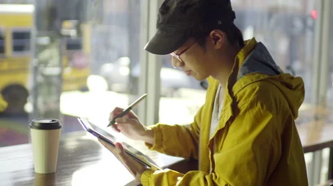 Multi-Ethnic Artist Draws On A Tablet In A Coffee Shop Video stock 47130188