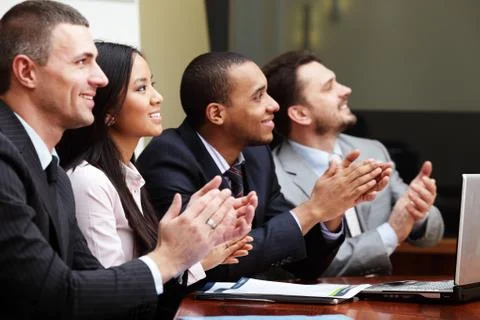 Multi ethnic business group greets somebody with clapping and smiling. focus  Stock Photos