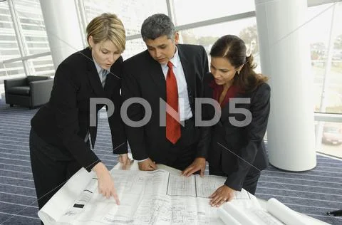 Multi-ethnic businesspeople looking at blueprints Stock Photos