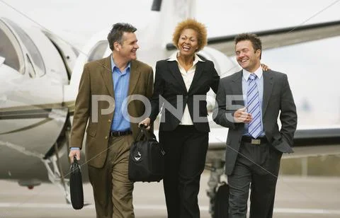 Multi-ethnic businesspeople walking away from airplane Stock Photos