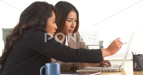 Multi-ethnic businesswomen doing research at desk Stock Photos