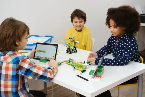 Multi ethnic children at technology lesson coding robot on tablet Stock Photos