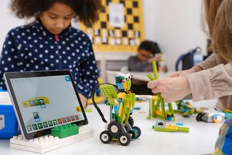 Multi ethnic children at technology lesson coding robot on tablet Stock Photos