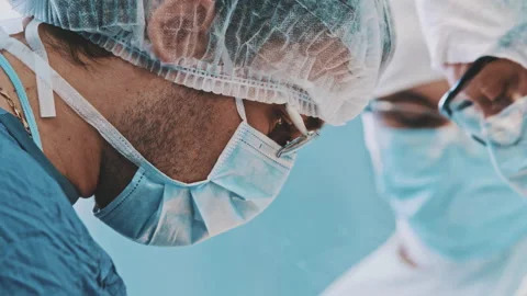 Multi-ethnic cooperating team of doctors and surgeons processing surgical Stock Footage 229907911