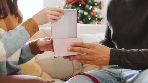 A multi-ethnic couple exchanges gifts around the Christmas tree during New Years Video stock 319969487