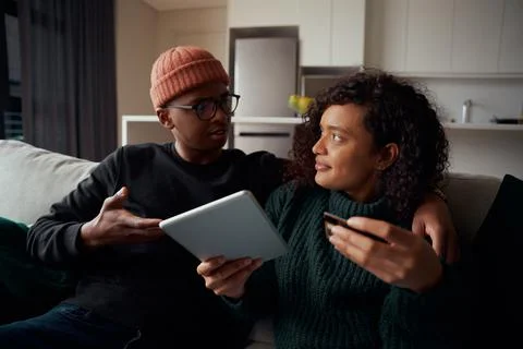Multi-ethnic couple fighting about purchasing goods online on tablet using Stock Photos