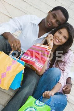 Multi-ethnic couple holding shopping bags Stock Photos