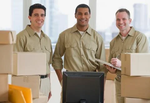 Multi-ethnic delivery men next to computer Stockfoto's