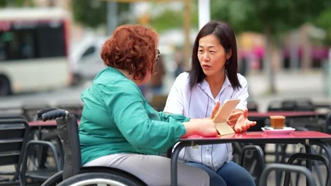 Multi-ethnic disabled friends talking using digital tablet in a cafeteria Stock Footage 291251072