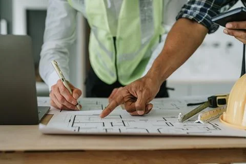 Multi ethnic engineer brainstorming and measuring for cost estimating on pa.. Stock Photos