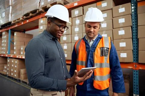 Multi ethnic factory engineers checking digital tablet at factory warehouse Stock Photos